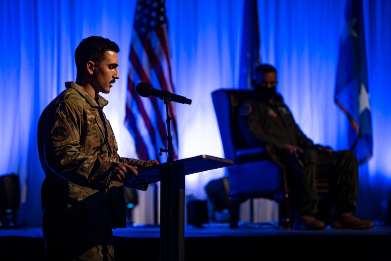 A photo of an Airman introducing special guests during a ceremony