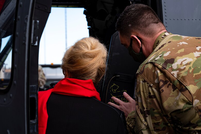A photo of an Airman showing a community leader a helicopter