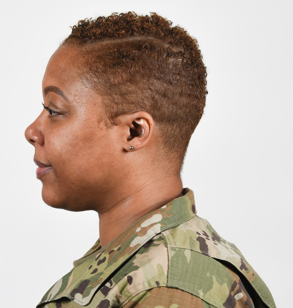 A female Soldier poses for an example photo with hair shorter than 1/4 inch, natural colored highlights, and earrings in the Army Combat Uniform, in support of an upcoming change in Army grooming and appearance standards.