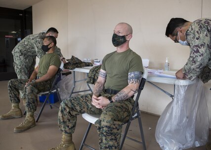 U.S. Marine Sgt. Maj. David Wilson, sergeant major of 3rd Marine Aircraft Wing (MAW) and U.S. Navy Command Master Chief Harlan Patawaran the wing command master chief of 3rd MAW prepare to receive round 1 the COVID-19 vaccination at Naval Medical Center San Diego, Jan. 22, 2020. Sgt. Maj. Wilson and Command Master Chief Patawaran both received the vaccines to ensure their own readiness as well as set the example for their Marines and sailors.
