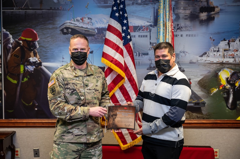 A U.S. Army commander and a safety officer hold and display an award.