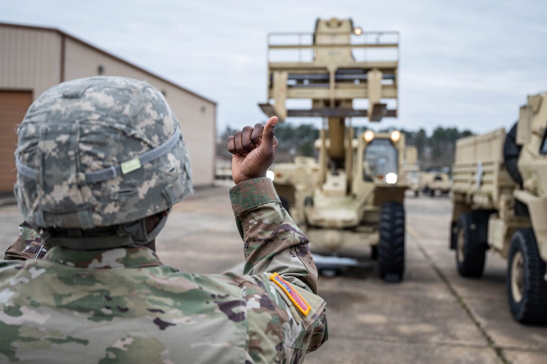 A Soildier guides another Soldier as they perform maintenance checks on a forklift.