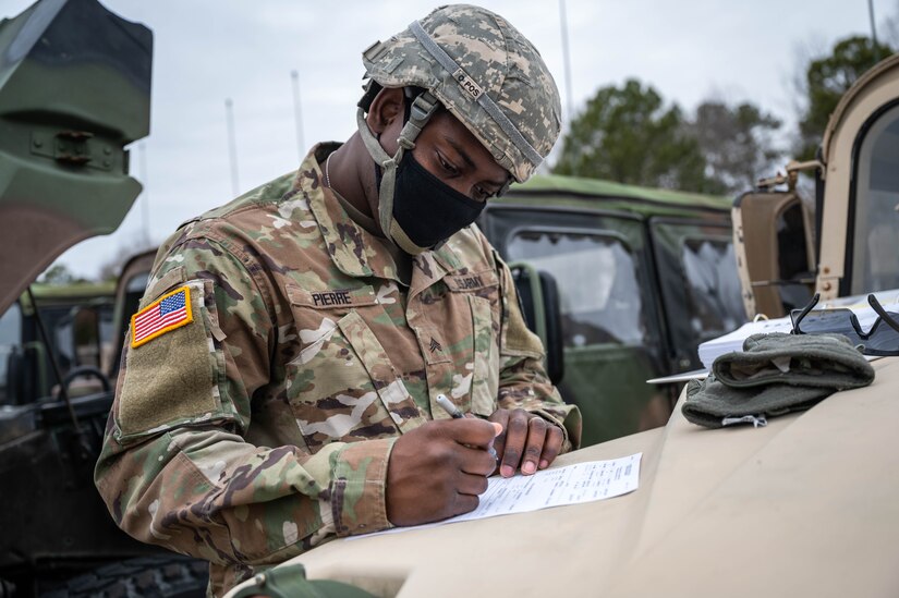 A Soldiers fills out a document on the hood of a Humvee.