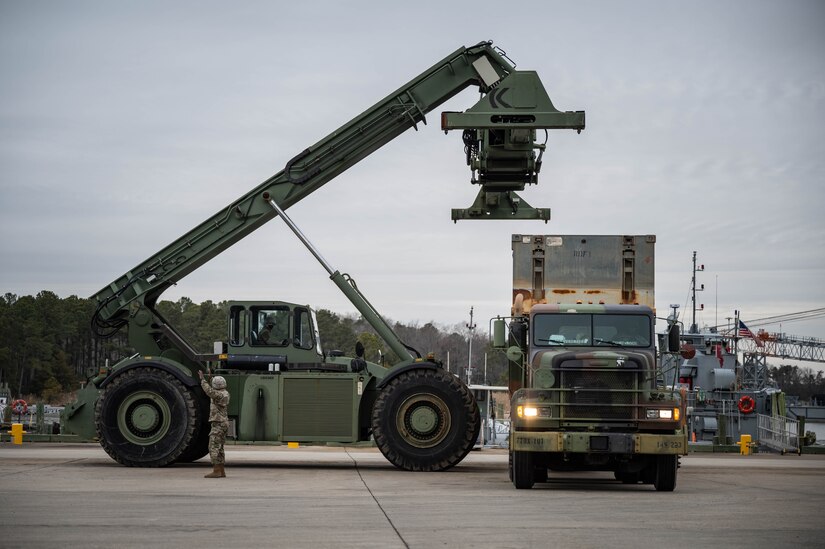 A crane put a container on a truck.