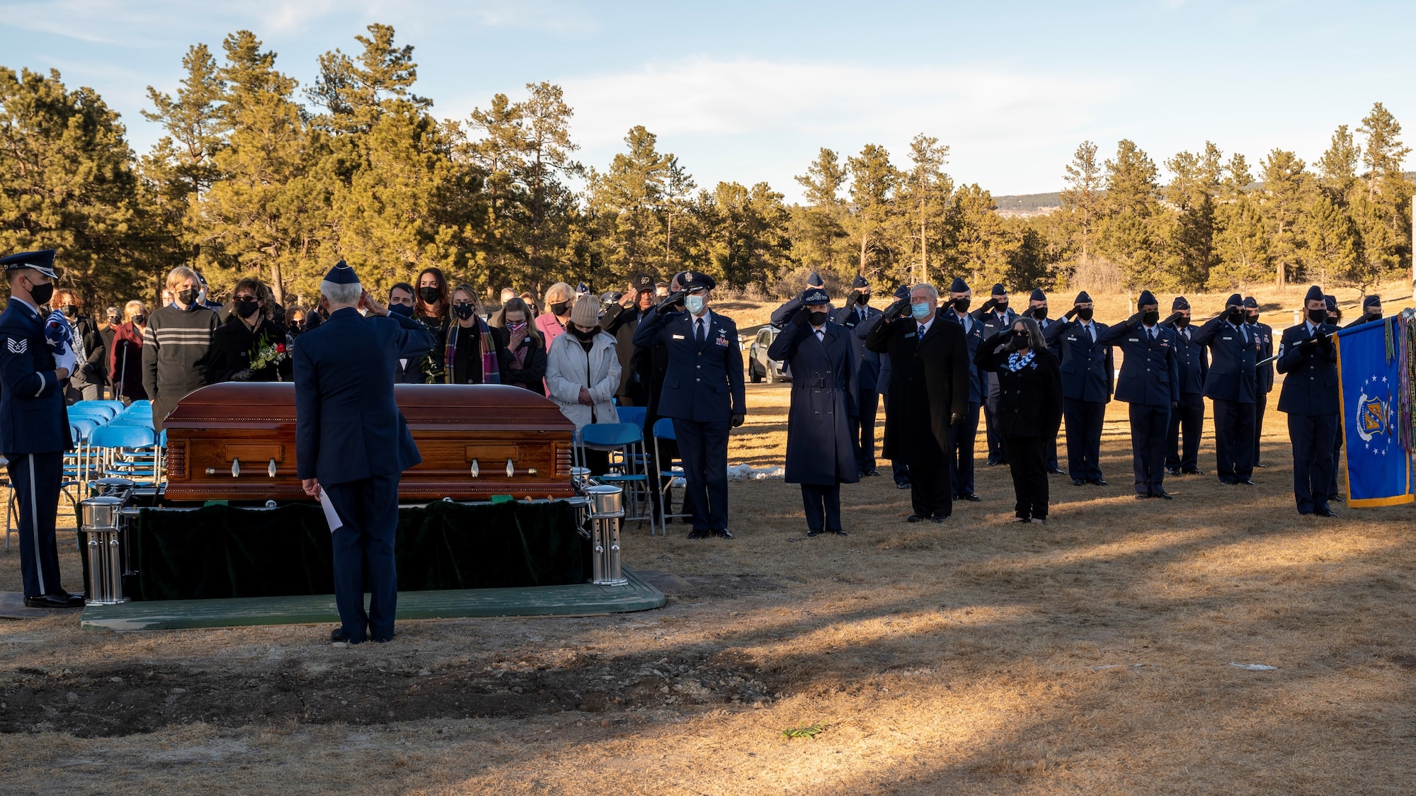 People watch as a burial casket is lowered during a funeral.