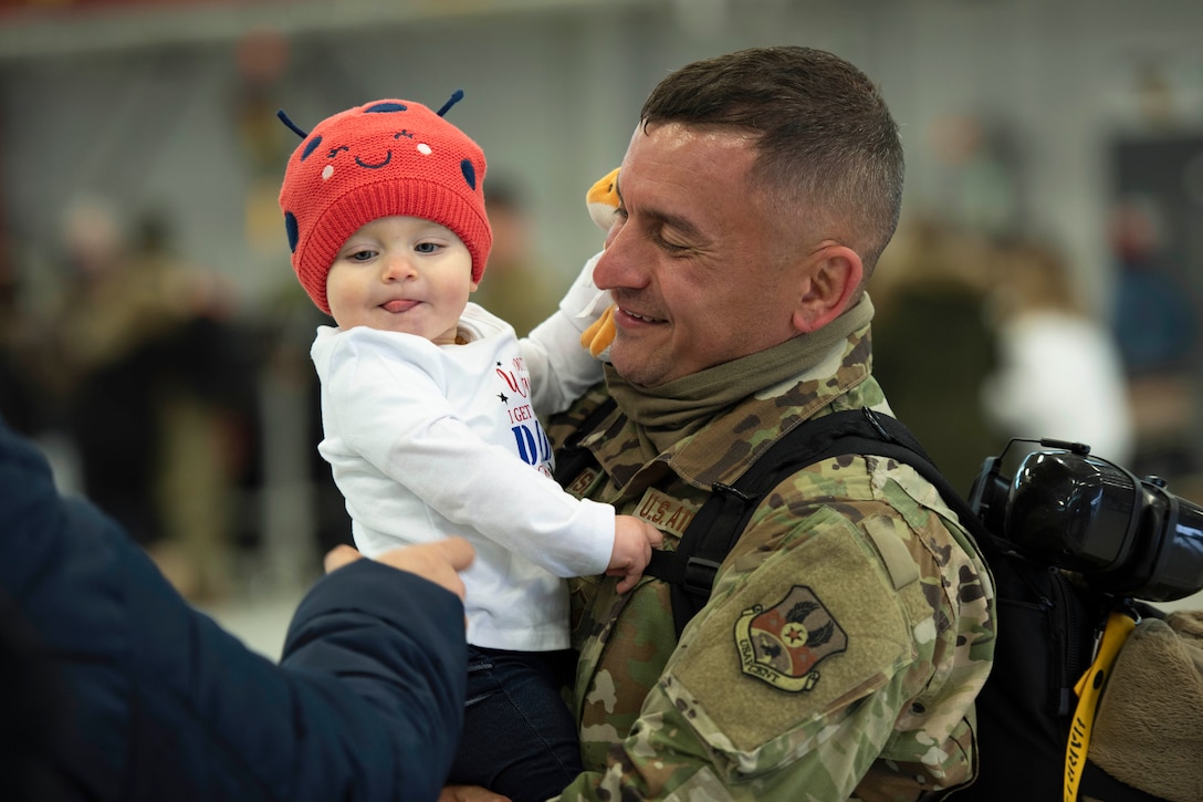 An airmen holds his daughter.