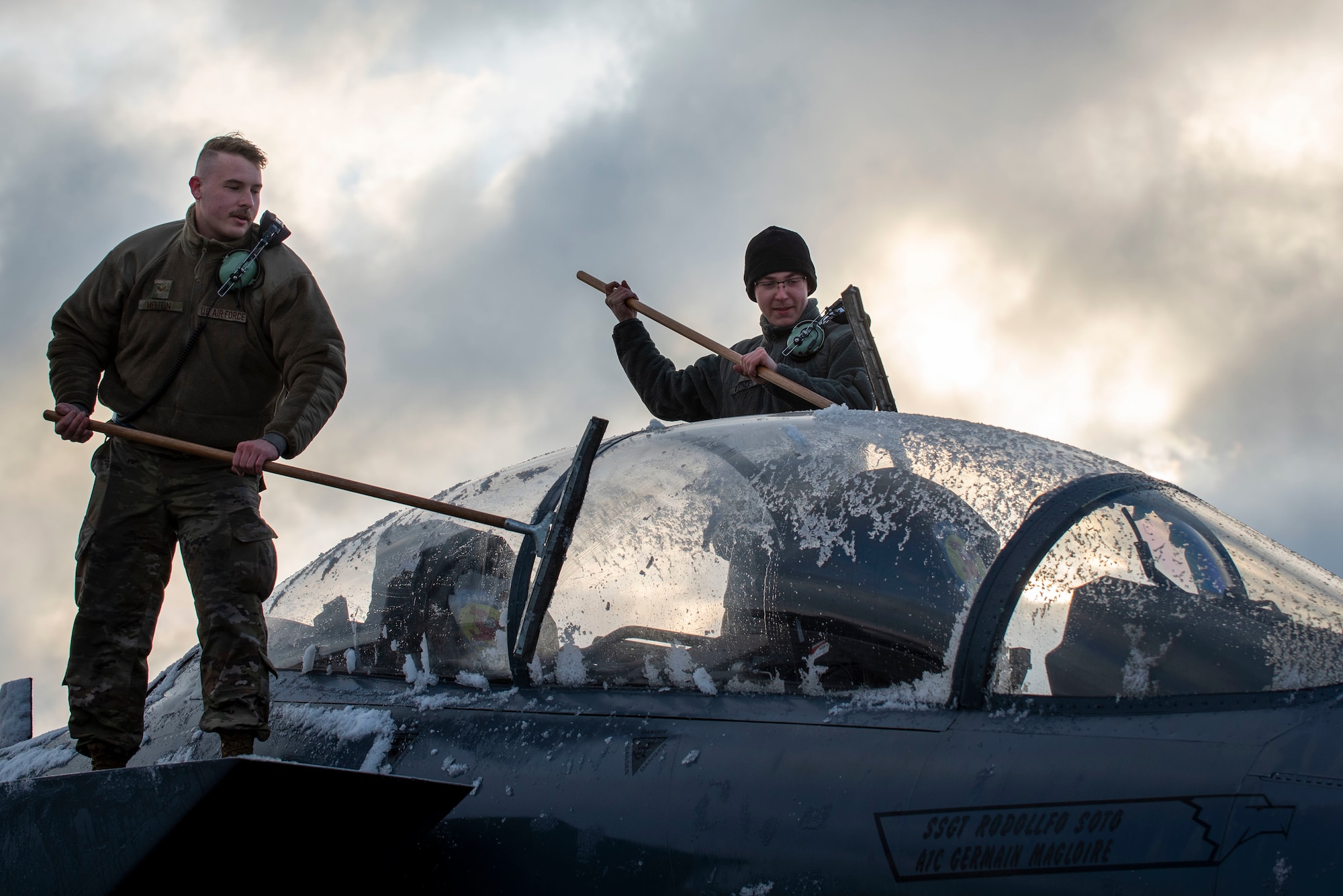 Senior Airman Collin Melton, 334th Aircraft Maintenance Unit avionics technician (left), and Senior Airmen Nicholas Verinder, 334th AMU avionics technician, clean snow off of an F-15E Strike Eagle at Seymour Johnson Air Force Base, North Carolina, Jan. 28, 2021.