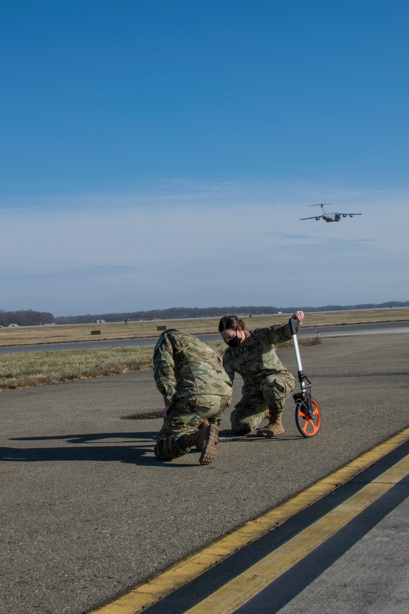 Senior Airman Kristina Grafton, 436th Operations Support Squadron airfield operations supervisor, and Senior Airman Keyton Nickell, 436th Airfield Operation Support Squadron airfield management shift lead, inspect a taxiway edge light at Dover Air Force Base, Delaware, Jan. 14, 2021. Airfield management conducts hourly runway inspections to ensure military, civilian, and foreign military aircraft can arrive and depart safely. Duties of the career also consist of coordinating with civil engineers, safety, air traffic control and various other base agencies to ensure safe aircraft operations within the airfield of Dover AFB. (U.S. Air Force courtesy photo by Airman 1st Class Carla Howard)