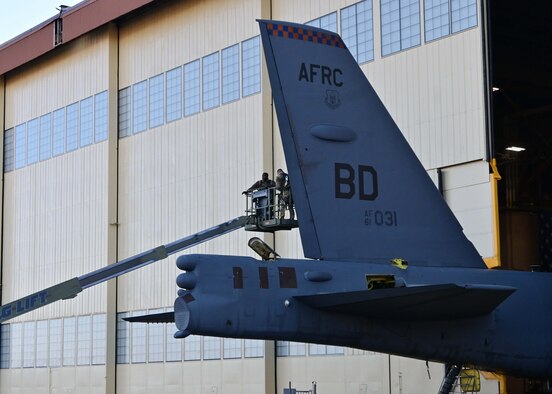 Airman on a lift work on the tail of a B-52.