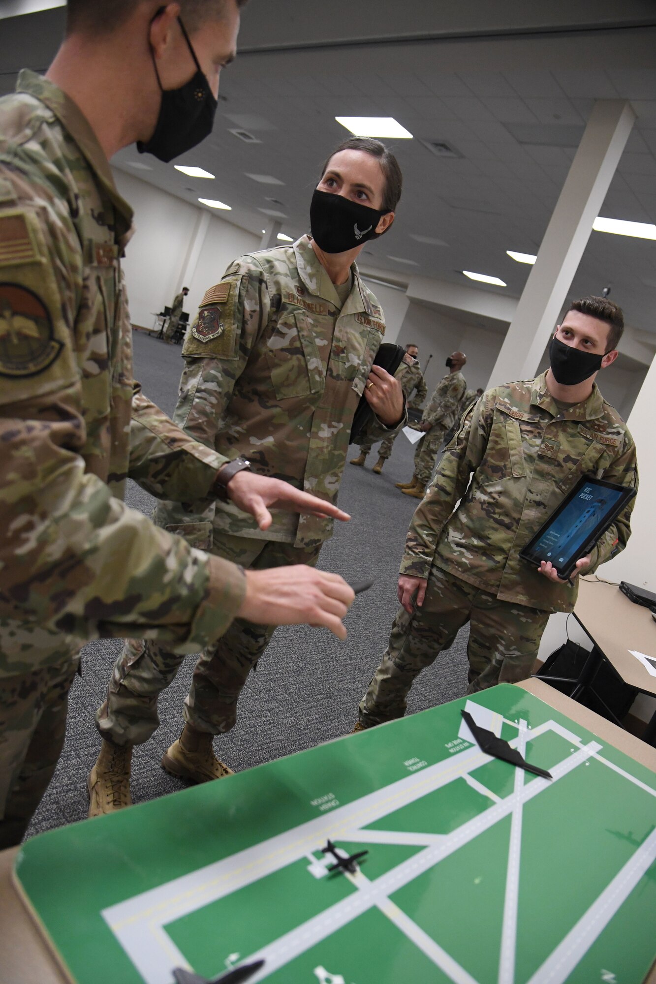 U.S. Air Force Master Sgt. Carlos Santiago, 334th Training Squadron air traffic control apprentice course superintendent, provides an "air traffic control pocket" mobile training application demonstration to Col. Heather Blackwell, 81st Training Wing commander, as Staff Sgt. Justin Leigh, 334th TRS instructor, stands by during the 81st Training Group Mock Tech Expo inside the Roberts Consolidated Aircraft Maintenance Facility at Keesler Air Force Base, Mississippi, Jan. 27, 2021. The 81st TRG level event was designed to prepare Keesler's nine innovation projects for the Air Education and Training Command level exposition. (U.S. Air Force photo by Kemberly Groue)