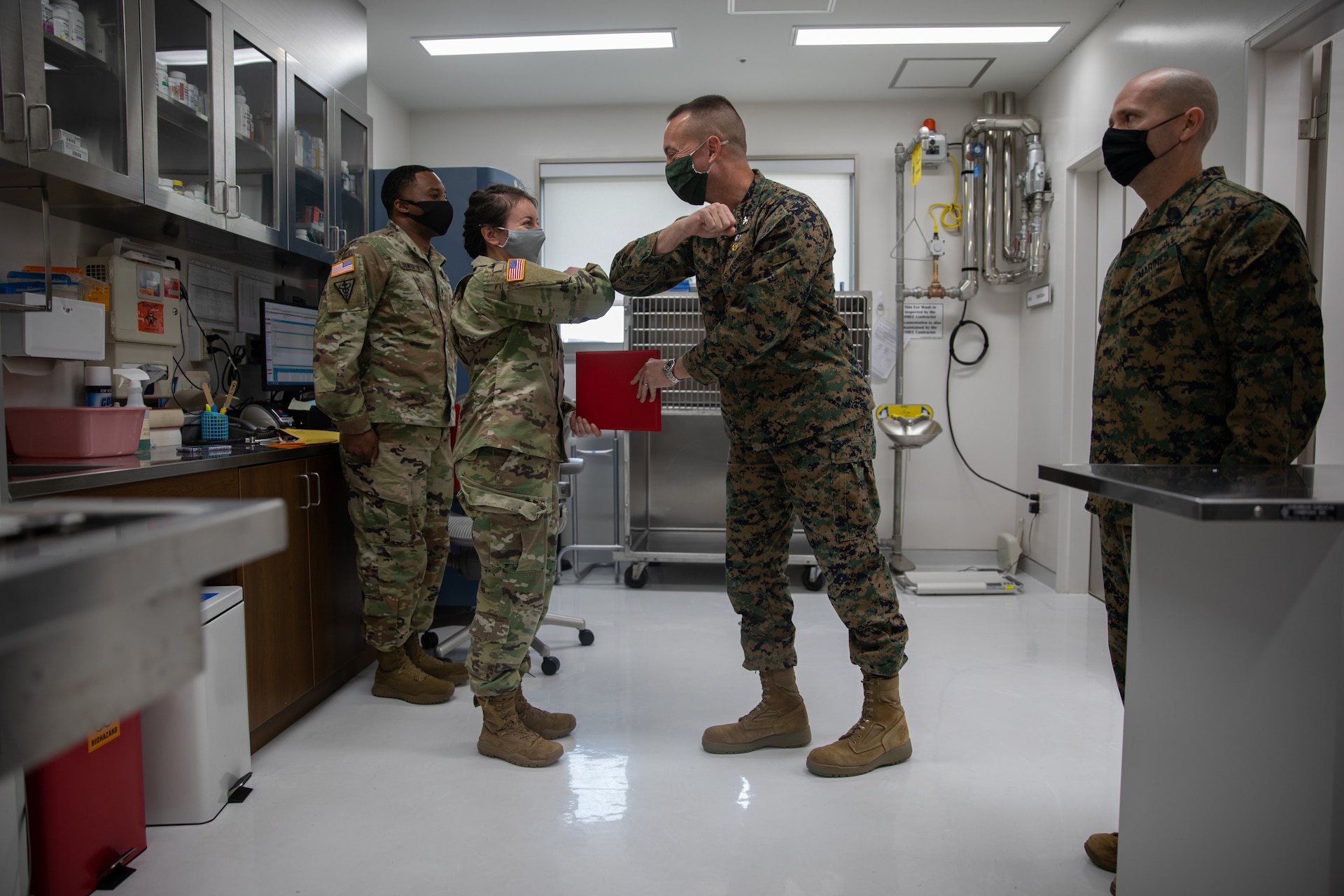 U.S. Marine Corps Col. Lance Lewis, center right, commanding officer of Marine Corps Air Station (MCAS) Iwakuni, hands an award to U.S. Army Capt. Austin Sorrels, center left, officer-in-charge of the Iwakuni Veterinary Treatment Facility (VTF) during a ceremony aboard MCAS Iwakuni, Jan. 7, 2021. The ceremony was held to present the VTF the Impact Iwakuni award for the impact they have made aboard the air station during the month of December. (U.S. Marine Corps photo by Lance Cpl. Triton Lai)