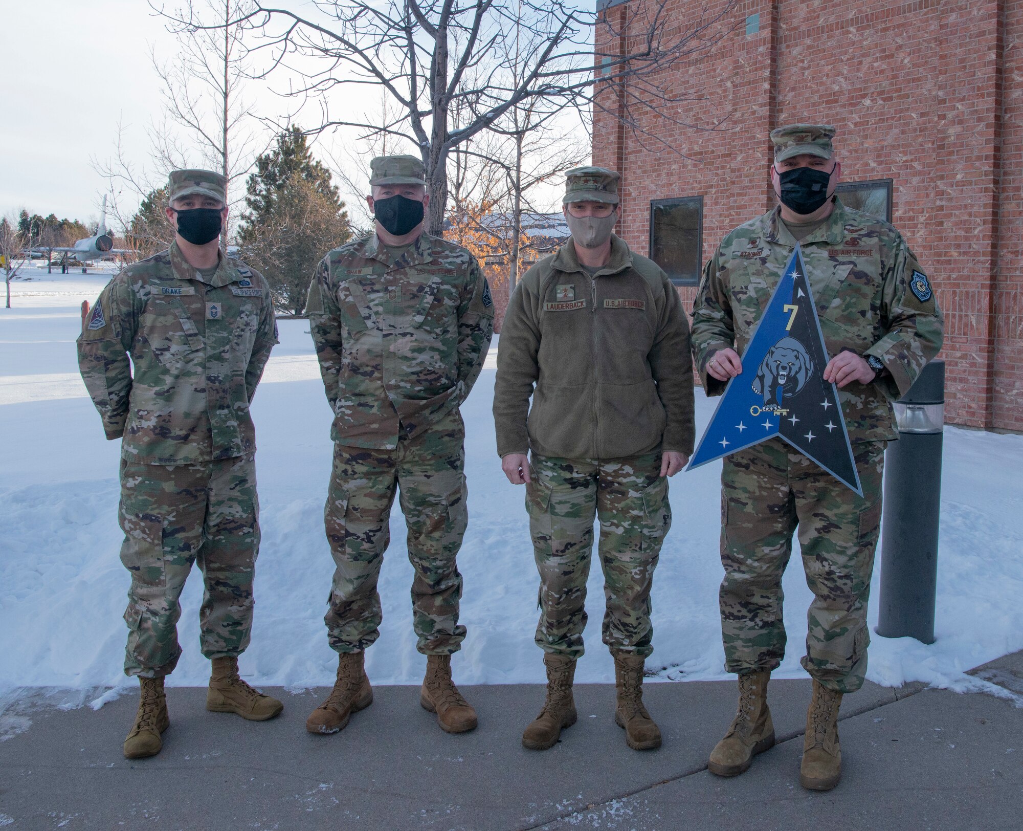 Picture of four military members in camouflage uniforms facing camera.