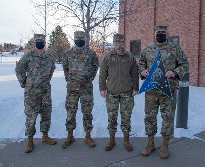 Picture of four military members in camouflage uniforms facing camera.