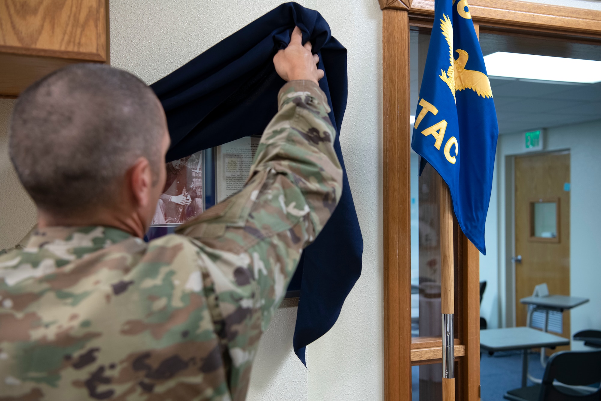 Senior Master Sgt. John Firlik, a career assistance advisor for the 718th Force Support Squadron, unveils a plaque dedicated to the first American enlisted Airman, Cpl. Edward Ward, for the classroom at the McDaniel Center at Kadena Air Base, Japan, Jan. 8, 2021. The open house was hosted to commemorate innovative historical figures, as well as inspire Airmen to be innovative. (U.S. Air Force Photo by Airman 1st Class Stephen Pulter)