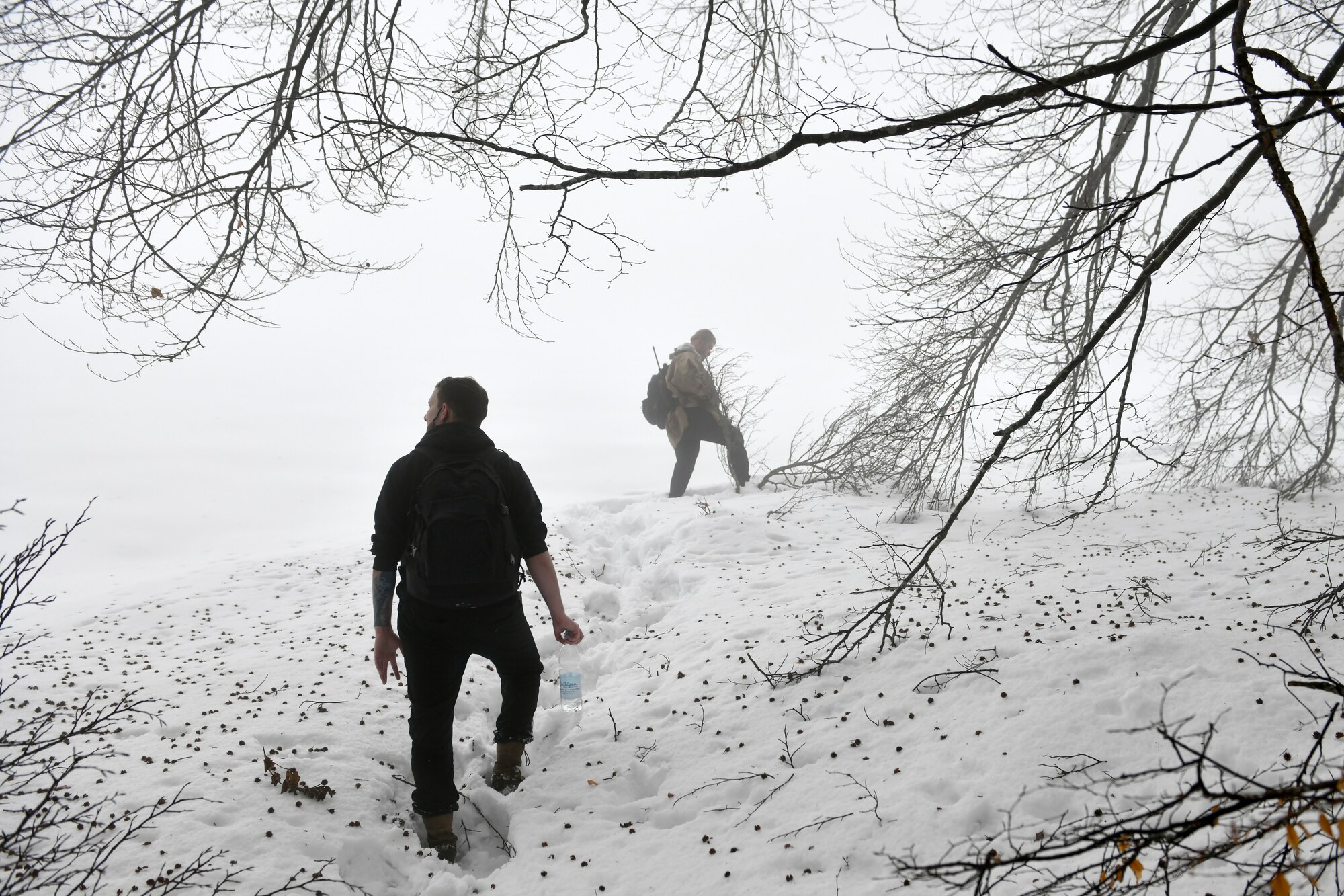 U.S. Air Force Senior Airman Niccolas Matranga, 31st Munitions Squadron munitions controller, left, and Airman 1st Class Jae Han, 31st Munitions Squadron precision guided missiles crew member, right, look for simulated ‘survivors’ during combat survival training in the mountains near Pian Cansiglio, Italy, Jan. 21, 2021. Matranga, Han and other Airmen participated in the exercise as the opposing forces, testing the survivors’ ability to evade pursuit while awaiting recovery. (U.S. Air Force photo by Staff Sgt. K. Tucker Owen)