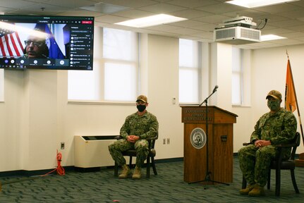 Rear Adm. Joseph DiGuardo, Commander Navy Expeditionary Combat Command, speaks via video conferencing technology, during a change of command ceremony for  Expeditionary Combat Readiness Center.