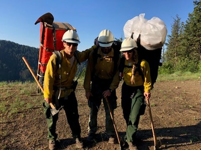 Three firefighters stand on a mountain