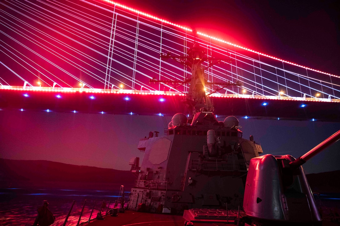 A ship transits the sea illuminated by red light.