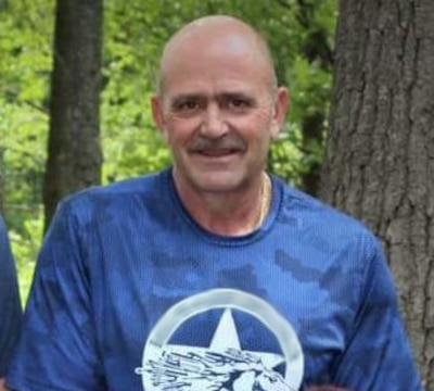 Mark Aicher wearing blue shirt with trees in the background