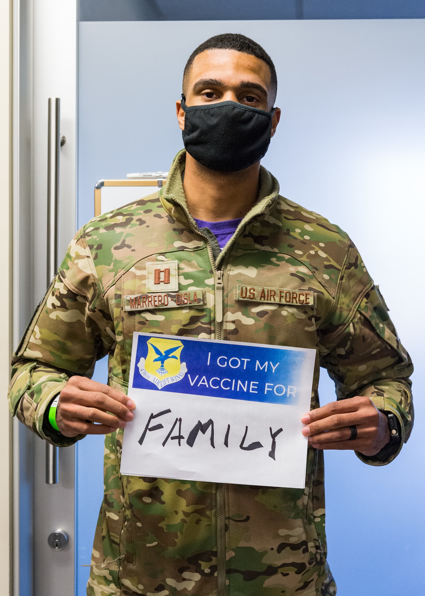Capt. Marcos Marrero-Disla, 3rd Airlift Squadron C-17 Globemaster III pilot scheduler, displays a sign stating why he volunteered for the COVID-19 vaccine Jan. 22, 2021, at Dover Air Force Base, Delaware. Marrero-Disla was among the first Team Dover front-line workers who voluntarily received the vaccine in accordance with Department of Defense guidance. The vaccine was granted emergency use authorization by the U.S. Food and Drug Administration for use in prevention of COVID-19. (U.S. Air Force photo by Roland Balik)