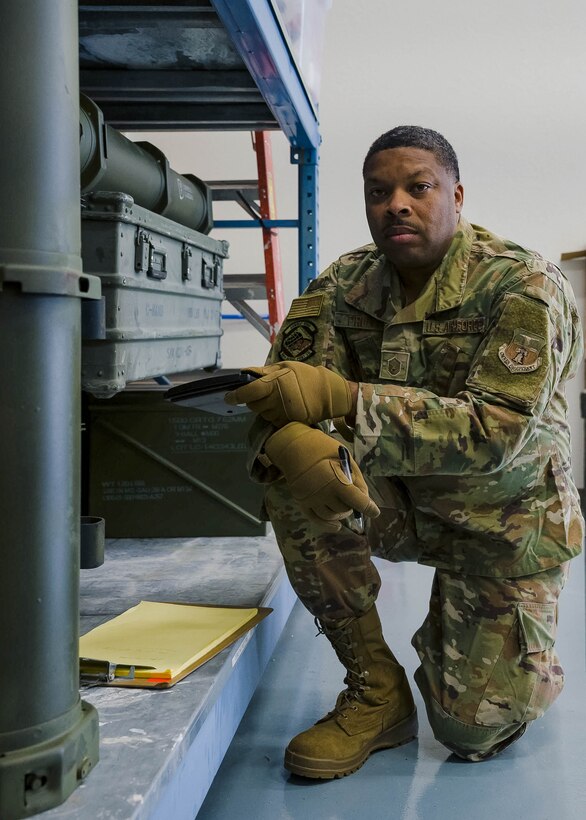 An Airman poses for a photo while inspecting equipment.