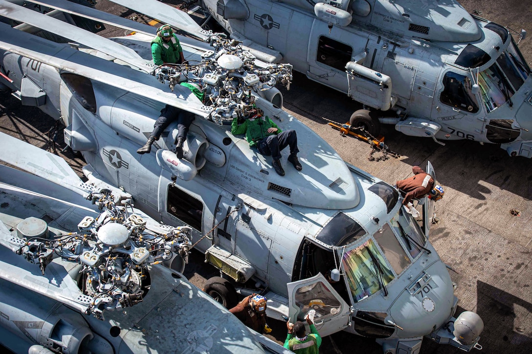 Sailors perform maintenance on a helicopter.