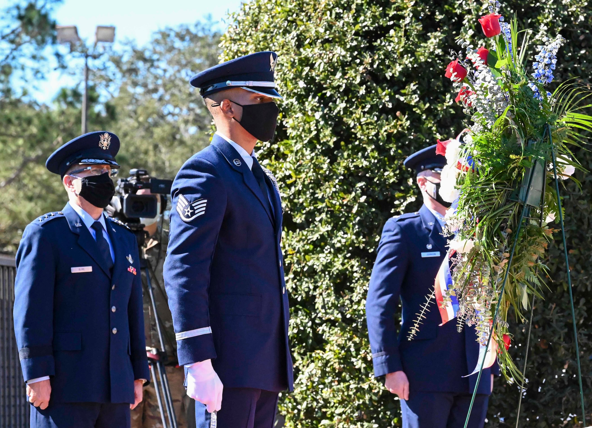 Uniformed members standing in front of a wreath.