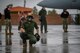 U.S. Navy Airmen stand on the flight line.