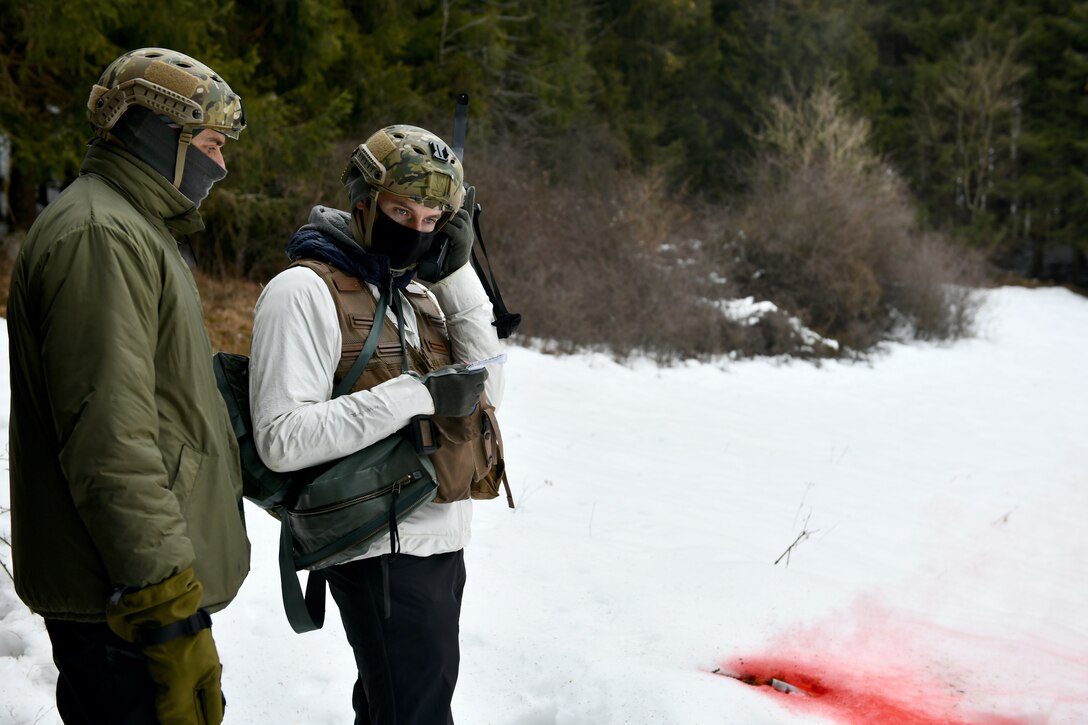 U.S. Air Force Capt. Bradley Beninati, 555th Fighter Squadron F-16 Fighting Falcon pilot, right, speaks to the crew of an HH-60G Pave Hawk via radio while Italian air force (ITAF) Primo Luogotenente Stefano B., left, 15th Wing, 81st Search and Rescue Training Center instructor, listens during combat survival training in the mountains near Pian Cansiglio, Italy, Jan. 21, 2021. The training took place on the third day of a week-long exchange between ITAF search and recovery personnel and 31st Fighter Wing survival, evasion, resistance and escape members. (U.S. Air Force photo by Staff Sgt. K. Tucker Owen)