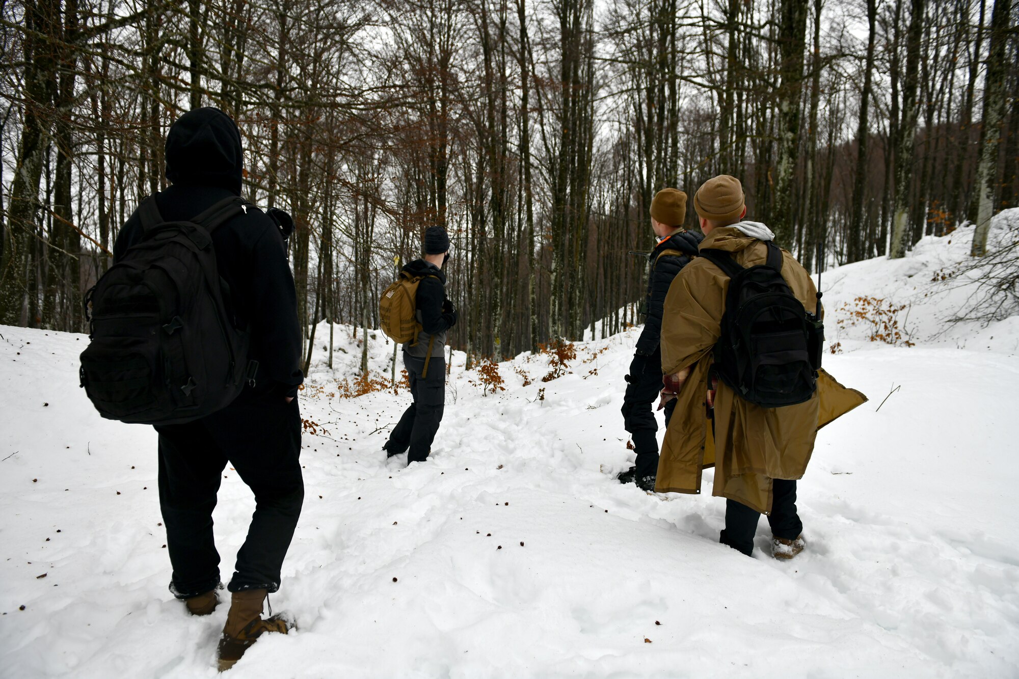 U.S. Airmen check for tracks in the snow during combat survival training in the mountains near Pian Cansiglio, Italy, Jan. 21, 2021. The Airmen acted as enemy forces attempting to locate survivors of a simulated crash, testing the survivors’ ability to evade pursuit while making their way to a predetermined rendezvous point – skills that could come in handy if they were to find themselves stranded in a contested environment. (U.S. Air Force photo by Staff Sgt. K. Tucker Owen)