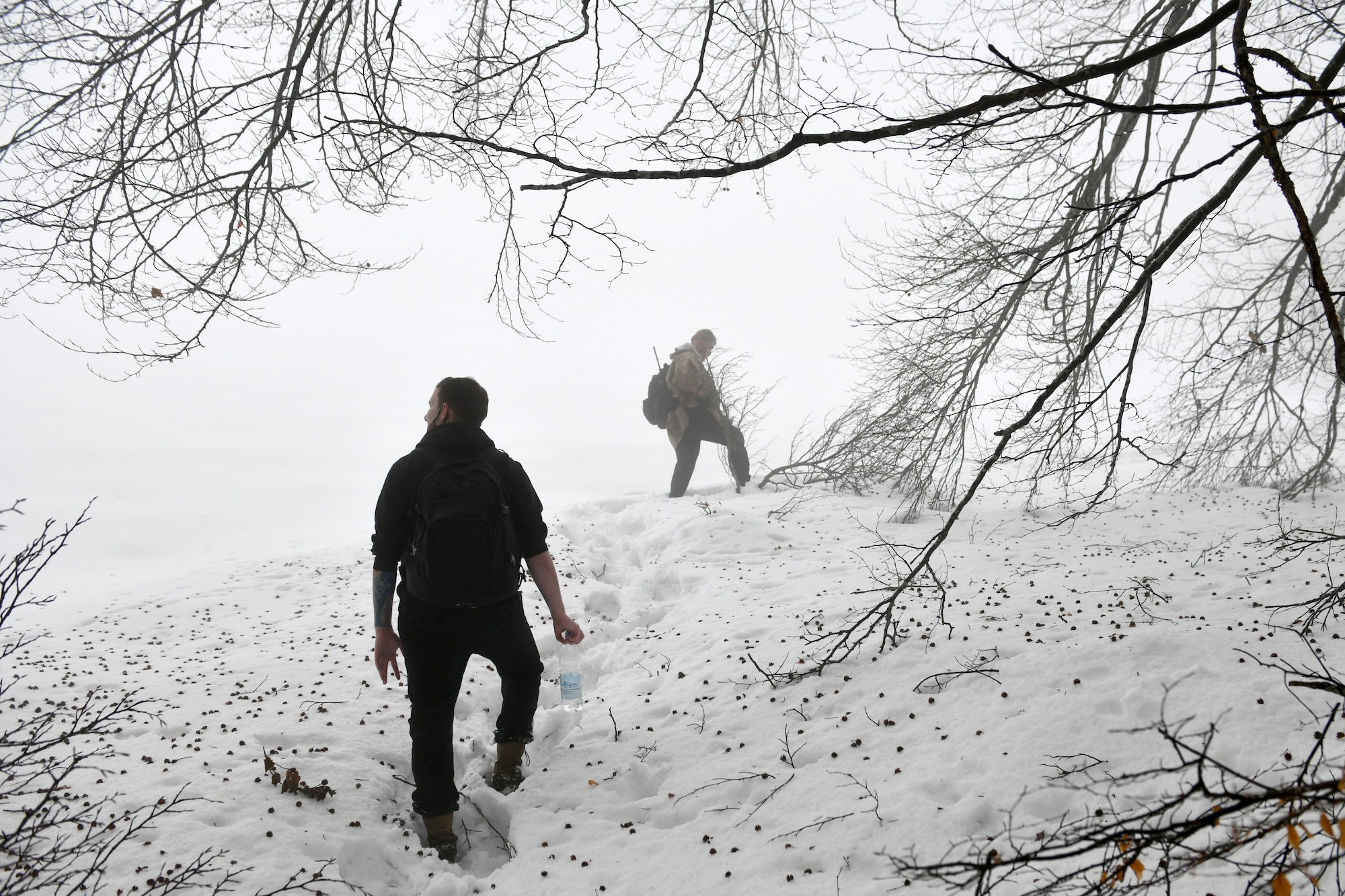 U.S. Air Force Senior Airman Niccolas Matranga, 31st Munitions Squadron munitions controller, left, and Airman 1st Class Jae Han, 31st Munitions Squadron precision guided missiles crew member, right, look for simulated ‘survivors’ during combat survival training in the mountains near Pian Cansiglio, Italy, Jan. 21, 2021. Matranga, Han and other Airmen participated in the exercise as the opposing forces, testing the survivors’ ability to evade pursuit while awaiting recovery. (U.S. Air Force photo by Staff Sgt. K. Tucker Owen)