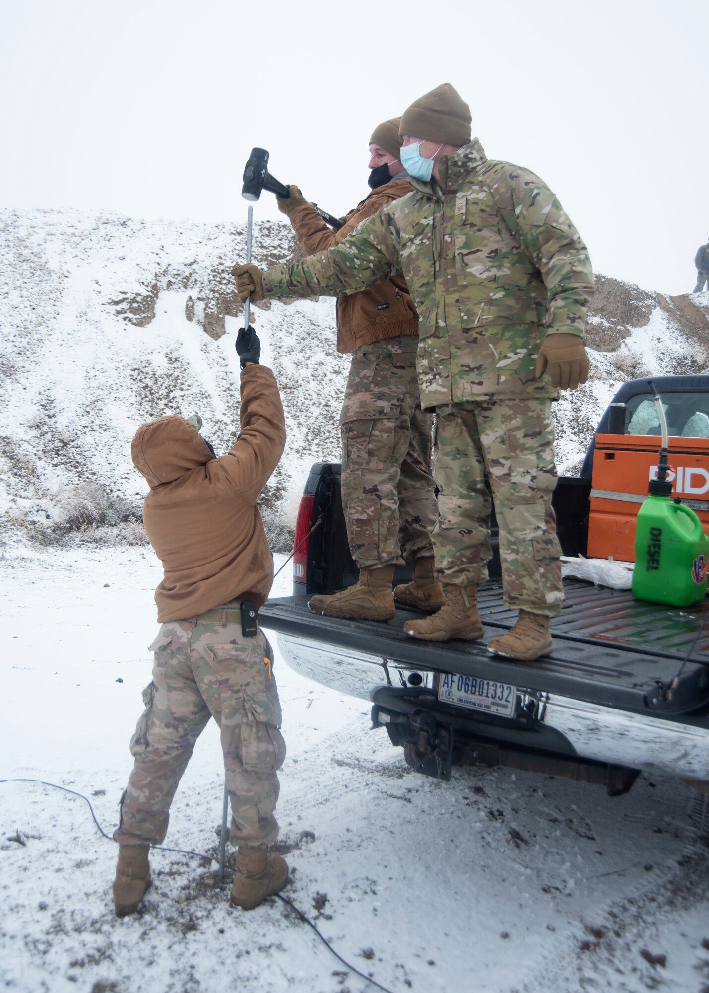 Three Airmen hammer down a grounding round with a hammer.