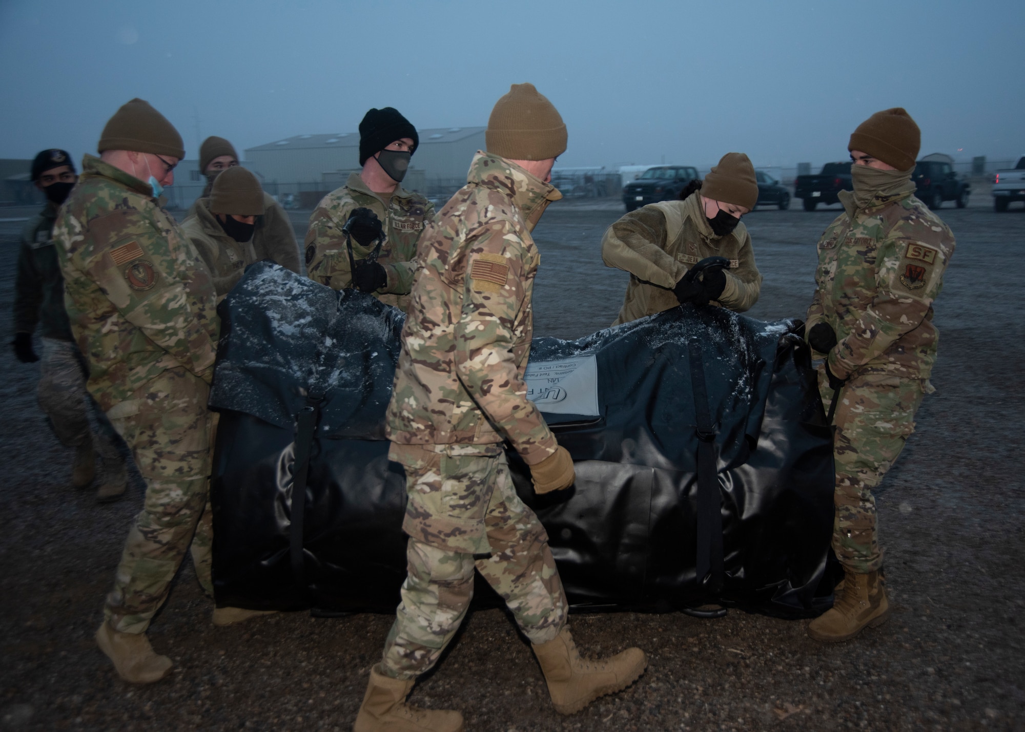 A group of Airmen lifts and a Tent Modular 60 shelter bag.