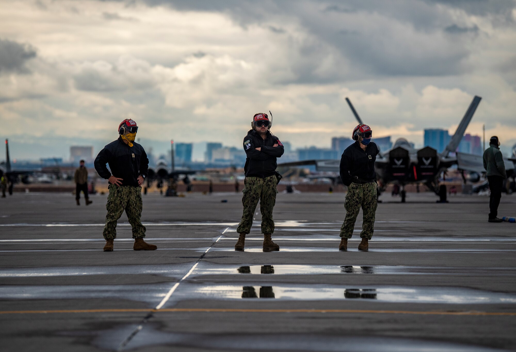 U.S. Navy Airmen stand on the flight line.
