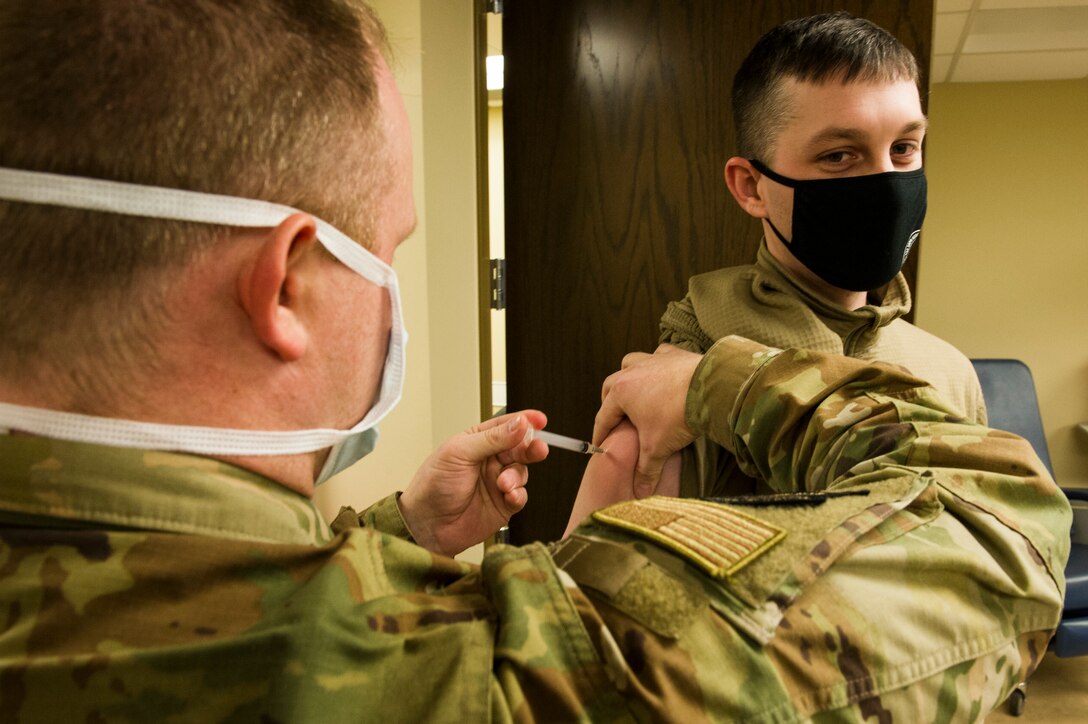 Tech. Sgt. Joshua Cox, 934th Civil Engineering Squadron emergency management squadron craftsmen, receives his COVID-19 vaccine from Senior Master Sgt. Bradly Mortenson, 934th Aeromedical Staging Squadron superintendent, at Minneapolis-St. Paul Air Reserve Station on Jan. 22, 2021. The 934th Airlift Wing initiated the distribution of the vaccine in an effort to combat the spread of the COVID-19 virus. (U.S. Air Force photo by Chris Farley)