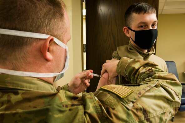 Tech. Sgt. Joshua Cox, 934th Civil Engineering Squadron emergency management squadron craftsmen, receives his COVID-19 vaccine from Senior Master Sgt. Bradly Mortenson, 934th Aeromedical Staging Squadron superintendent, at Minneapolis-St. Paul Air Reserve Station on Jan. 22, 2021. The 934th Airlift Wing initiated the distribution of the vaccine in an effort to combat the spread of the COVID-19 virus. (U.S. Air Force photo by Chris Farley)