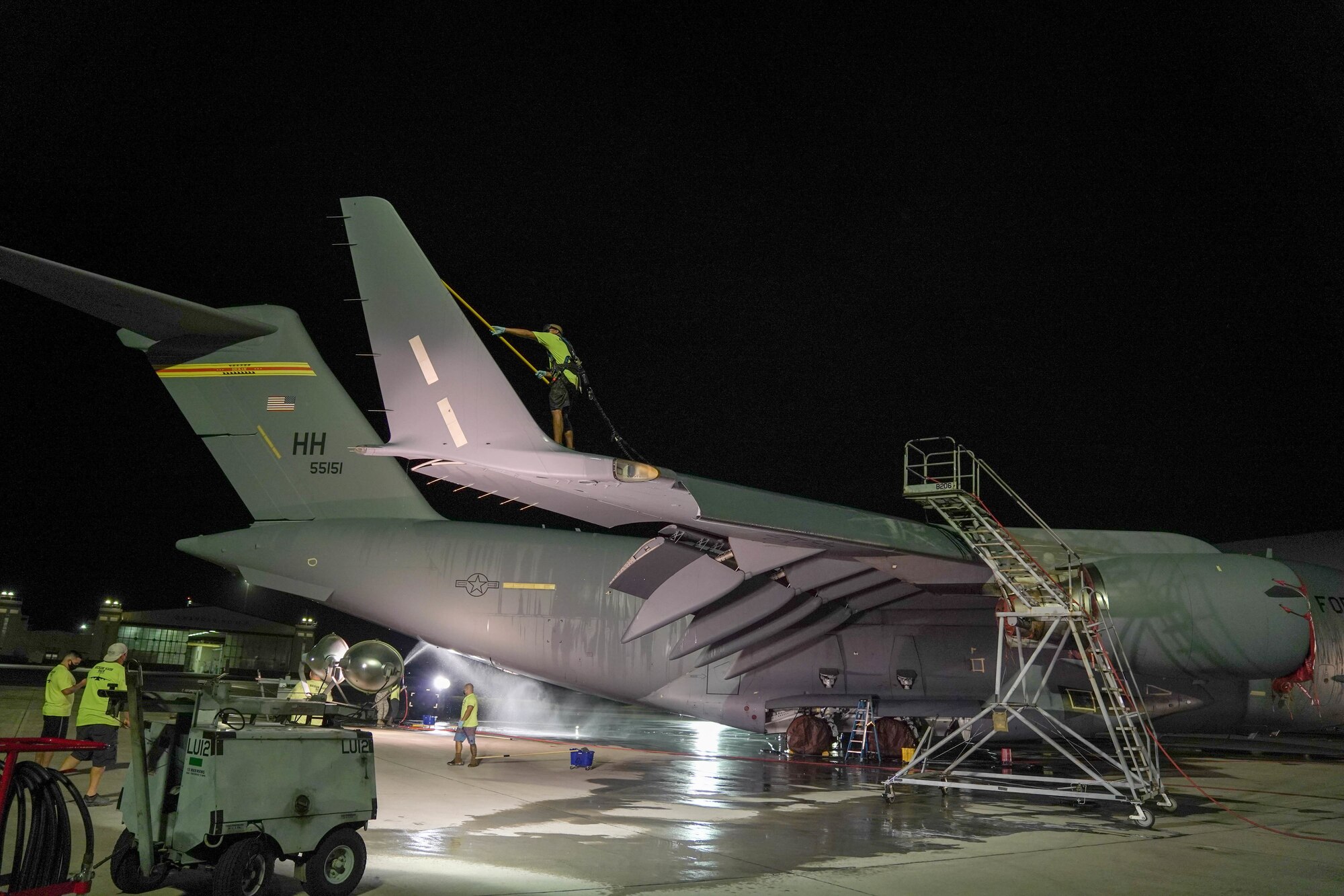 A contractor from the 15th Aircraft Maintenance Squadron washes a C-17 during a bird bath on the flightline at Joint Base Pearl Harbor-Hickam, Jan. 7, 2021. Aircraft undergo routine cleanings to prevent saltwater corrosion. (U.S. Air Force photo by Airman 1st Class Makensie Cooper)