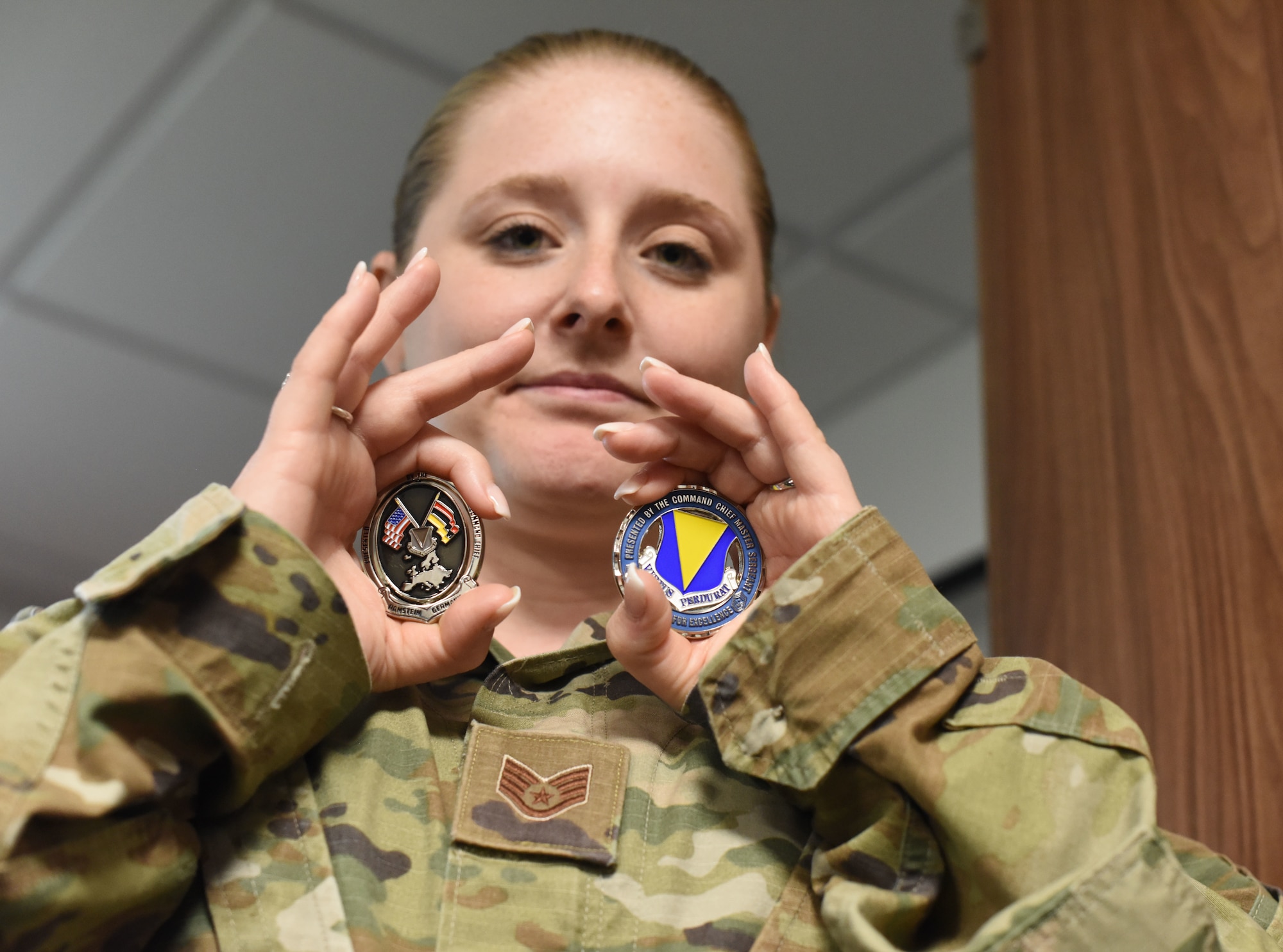 Staff Sgt. Lisa Niel, 86th Material Maintenance Squadron noncommissioned officer in charge of fleet maintenance and analysis, holds up two coins at Ramstein Air Base, Germany, June 24, 2021. Niel earned the title of Airlifter of the Week for her hard work and dedication to the 86th Airlift Wing’s mission. (U.S. Air Force photo by Senior Airman Thomas Karol)