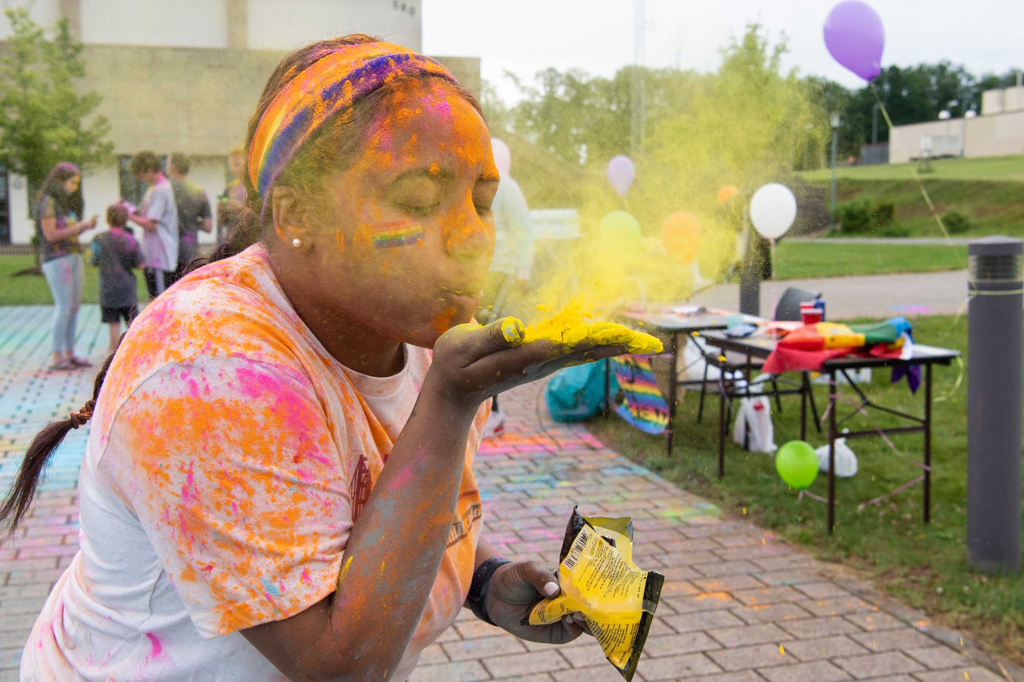 U.S. Air Force Tech. Sgt. Jahairy Casado, 52nd Civil Engineer Squadron NCO  in charge of service contracts, blows colored powder in the air during a color run, June 30, 2021, on Spangdahlem Air Base, Germany. During lesbian, gay, bisexual, transgender, and queer Pride Month, the United States reflects on individuals who continue to fight for equality and for the ability to live freely as U.S. citizens. (U.S. Air Force photo by Staff Sgt. Melody W. Howley)
