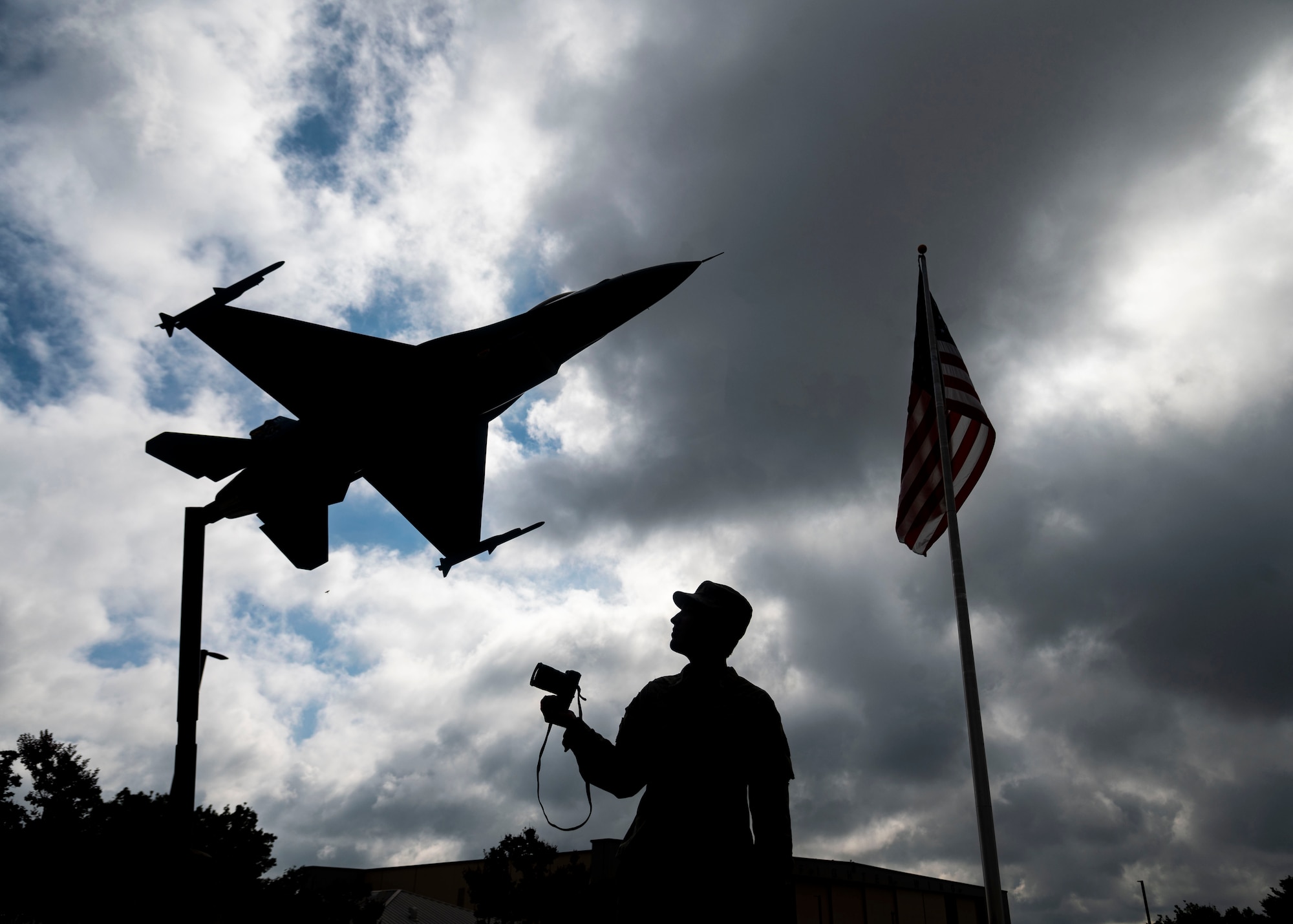 A silhouetted photo of an Airman next to a static display.