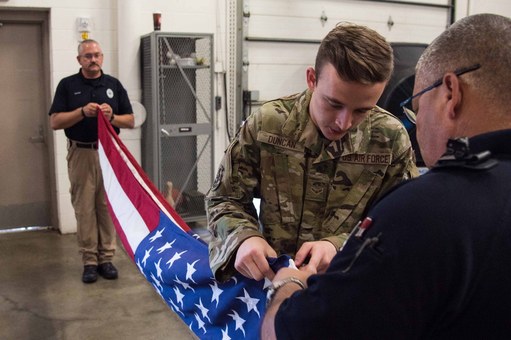 Airman 1st Class Brandon Duncan, 22nd Force Support Squadron honor guardsman, assists Sgt. Benjamin Romero, Sedgwick County honor guardsman, and Detective Jeremy Noel, Sedgwick County honor guard commander, during their visit to McConnell Air Force Base, Kansas, June 30, 2021. Eight members of both the Wichita City Police and Sedgwick County Honor Guards visited McConnell and learned from the 22nd Air Refueling Wing’s honor guard members. (U.S. Air Force photo by Senior Airman Alexi Bosarge)