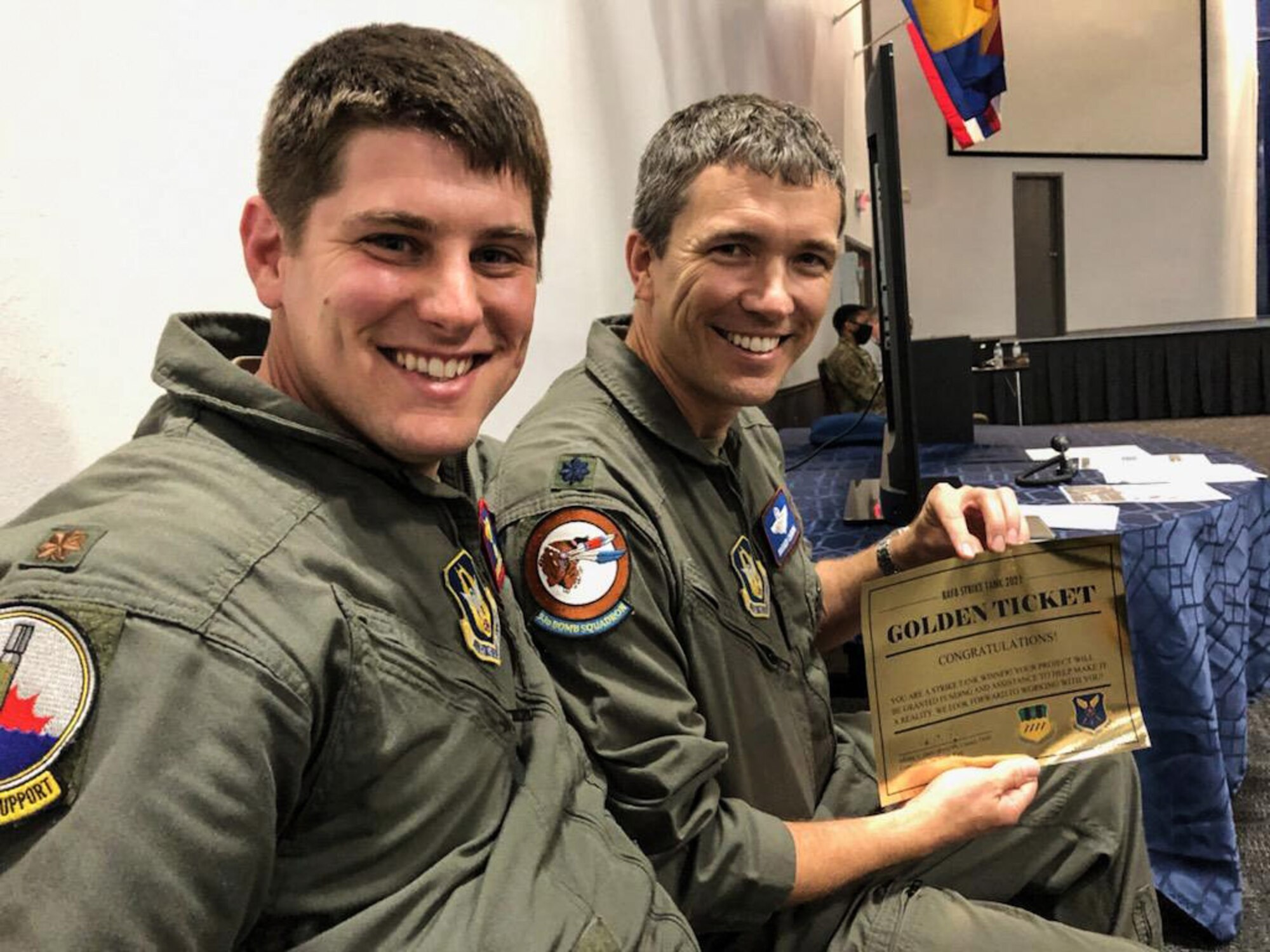 Photo of two Airman smiling and holding a certificate.