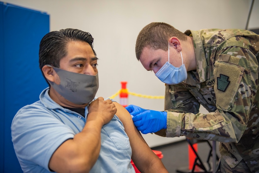 Spc. Christopher Valencia, combat medical specialist with Headquarters and Headquarters Company, 1st Battalion, 112 Infantry Regiment administers a COVID-19 vaccine to Romero Sergio at the Esperanza Community Vaccination Center in Philadelphia ON May 17, 2021. The Pennsylvania National Guard has been supporting COVID-19 vaccine sites across the Commonwealth since mid-March. PA Guard members have supported the administration of more than 500,000 COVID-19 vaccine doses. (Air National Guard photo by Staff Sgt. Ross Alexander Whitley / 111th Attack Wing)