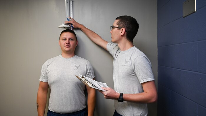 Staff Sgt. Benjamin Larson has his height recorded by Tech. Sgt. Alexander House inside a training room.