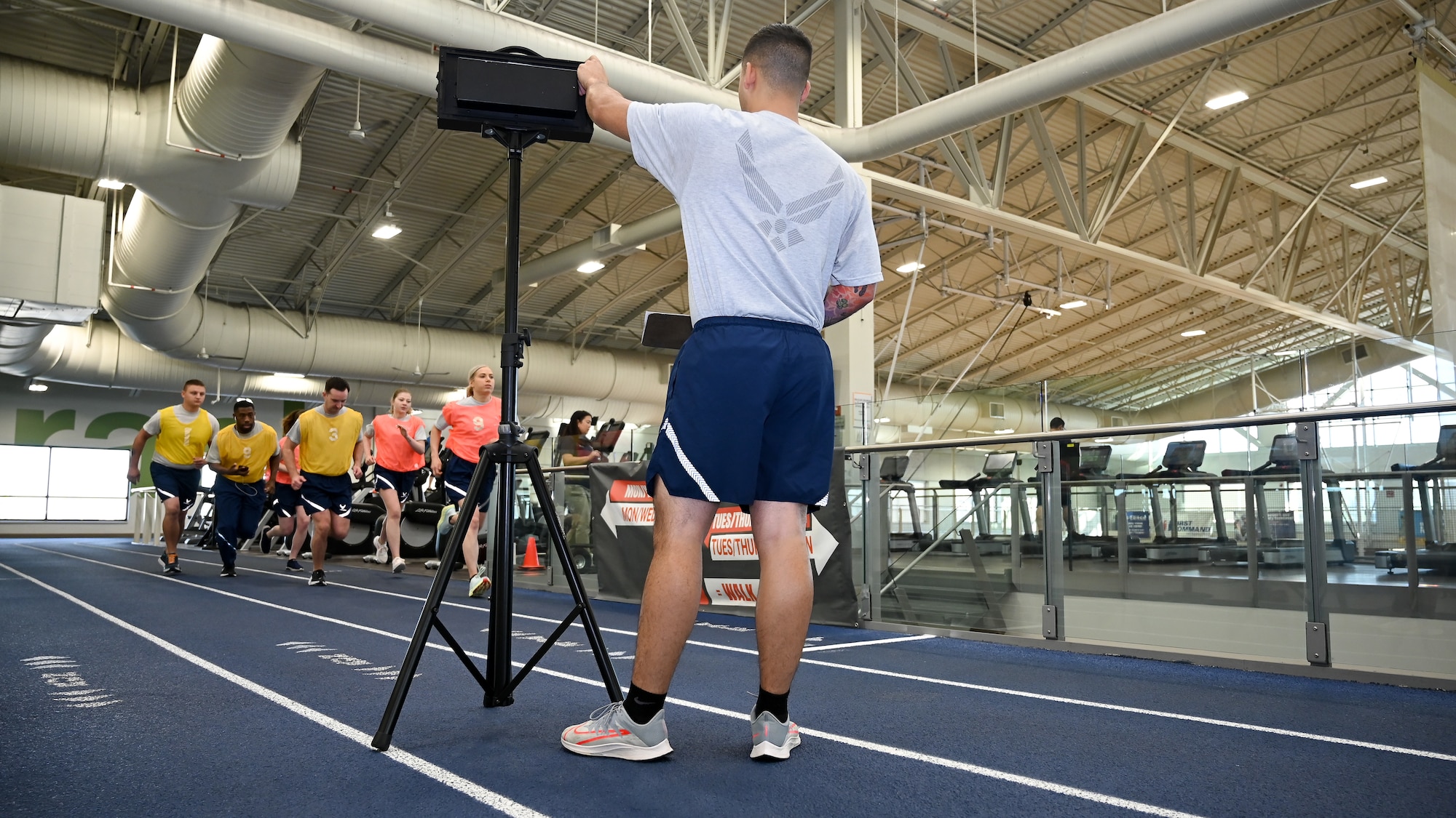An Airman watches in the foreground as a group of Airmen begin their 1.5-mile run.