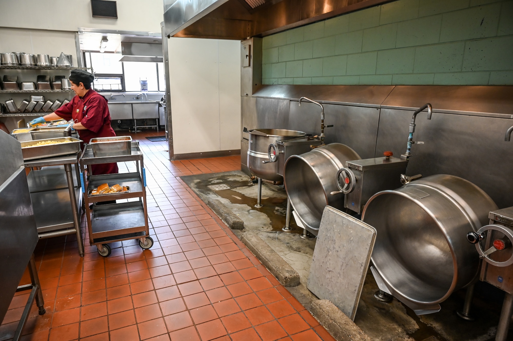 A food service worker moves a tray in the back kitchen.