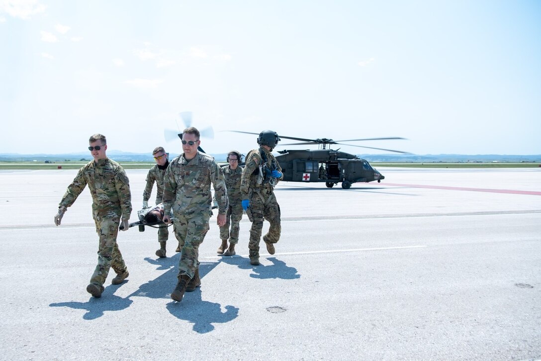 Participants in exercise Golden Coyote carry a simulated injured Army National Guardsman across the flight line on Ellsworth Air Force Base, S.D., June 16, 2021.