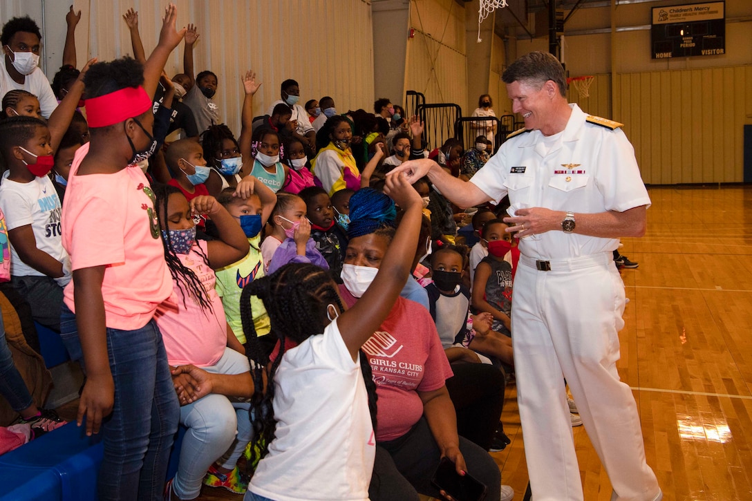 A sailor interacts with a group of children.