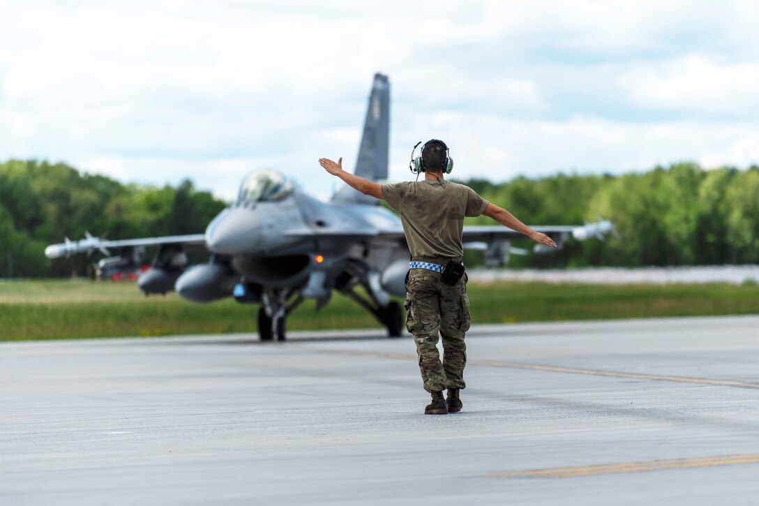 Photo of U.S. Airmen marshals aircraft.