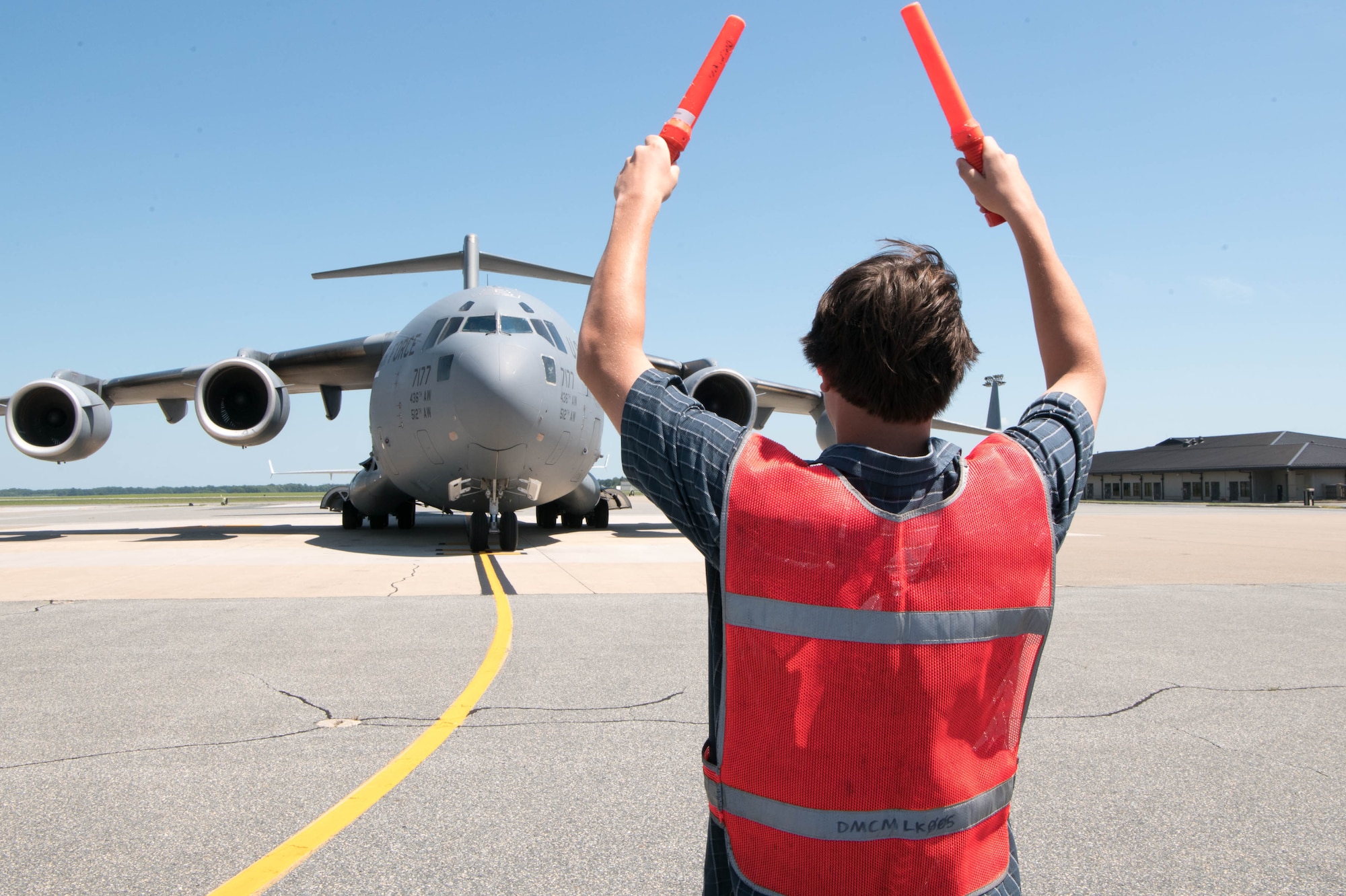 Tyler Peeler marshals a C-17 Globemaster III piloted by his father, Col. Mike Peeler, 436th Operations Group commander, during his final flight as group commander at Dover Air Force Base, Delaware, June 30, 2021. Peeler served as commander for two years. (U.S. Air Force photo by Mauricio Campino)